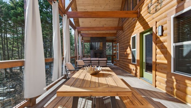 Un terrazzo in legno con tavolo e panche, affacciato su una zona boschiva.