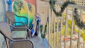 A balcony with two surfboards, wicker chairs, and a view of the cityscape. - Bright condo in beautiful Honolulu with cool AC breeze (Honolulu)
