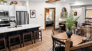Een moderne keuken met een centraal eiland, roestvrijstalen apparatuur en een eethoek met een houten tafel en stoelen.