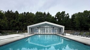Una piscina con zona techada y sillas de descanso.