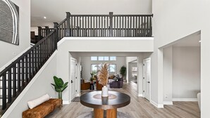 Ein großzügiges, modernes Interieur mit einem runden Tisch in der Mitte, einer Treppe und Blick zum Obergeschoss.
