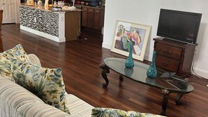 Ein Wohnzimmer mit einer Couch, einem Couchtisch, einem Fernseher und einer Deckenleuchte.