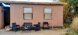 A rustic building with two windows, a small table, and two chairs.