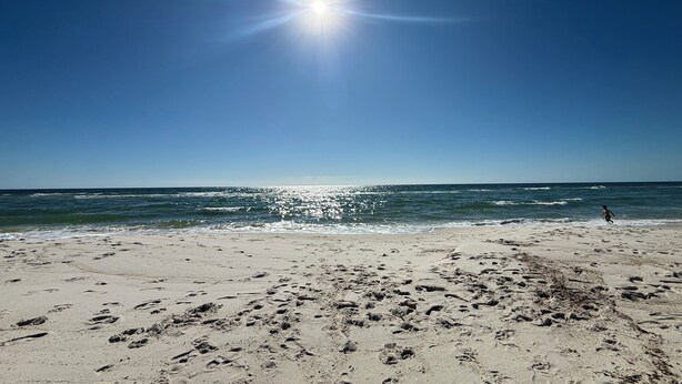 A beach with footprints and a person running towards the water. - Gulfview Paradise in Lost Key (Pensacola)
