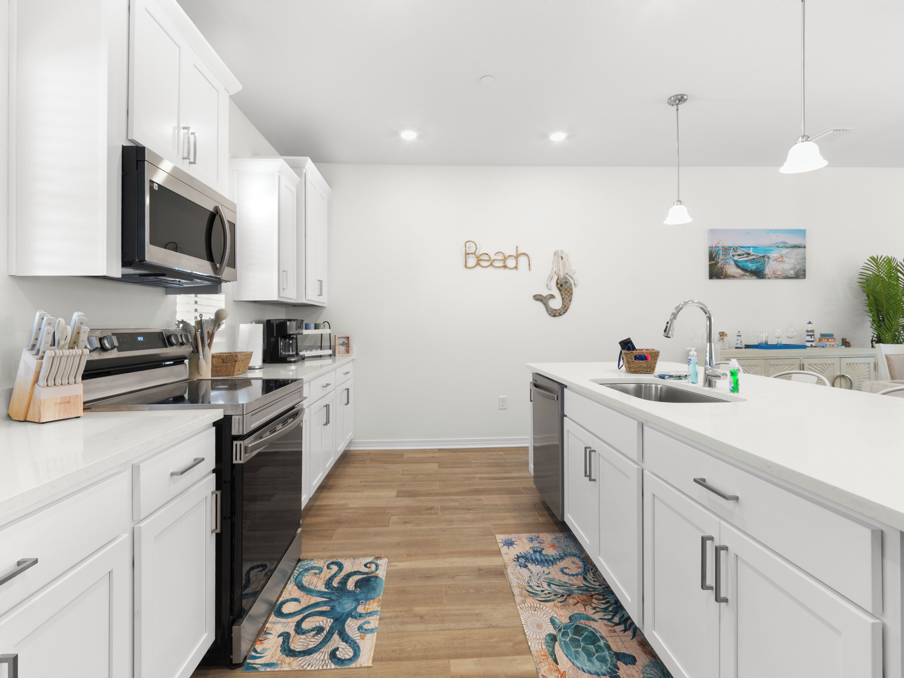 Una cocina moderna con armarios blancos, electrodomésticos de acero inoxidable y piso de madera.