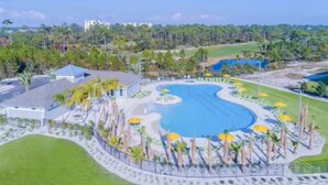 A resort with a large swimming pool, palm trees, and a golf course in the background. - Gulfview Paradise in Lost Key (Pensacola)