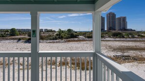 A beach view from a covered porch with a view of high-rise buildings in the distance. - Gulfview Paradise in Lost Key (Pensacola)