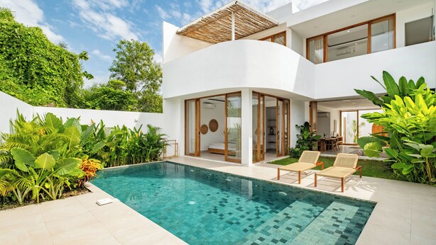 Ein modernes, zweistöckiges Haus mit Schwimmbad, großen Fenstern und üppiger Bepflanzung.