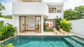 Ein modernes Haus mit Swimmingpool, einem Schlafzimmer mit Schiebetür und einem Balkon mit Liegestühlen.
