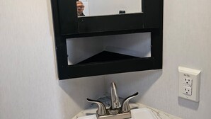 Ein Badezimmer mit einem weißen Waschbecken, einem schwarzen Medikamentenschrank und einem Spiegel.