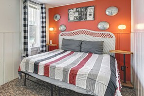 Un lit avec une couvre-lit à rayures, une tête de lit en osier blanche et deux tables de chevet avec des lampes.
