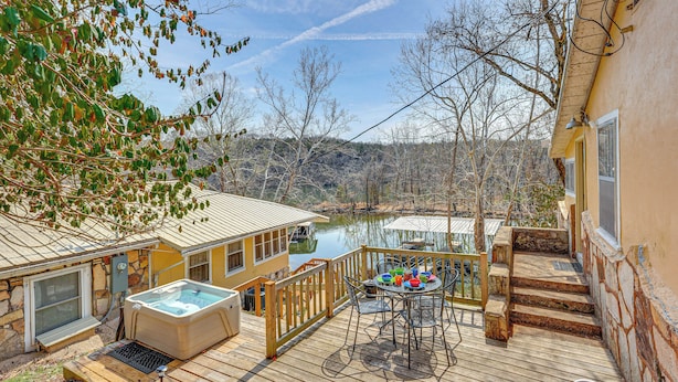 A deck with a hot tub, outdoor table, and chairs, overlooking a body of water and a forested area. - Boat & Fish! 1950s Rockaway Beach Cabin w/ Hot Tub (Rockaway Beach)