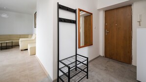 Une pièce avec une étagère en métal noir, une porte en bois et un canapé beige.