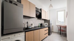 Une cuisine de taille réduite, équipée d’un lave-linge, d’un four à micro-ondes et de meubles de rangement en bois.