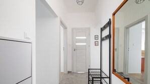 Un couloir avec une armoire à miroir, un portant métallique et une porte donnant sur une autre pièce.