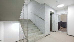 A modern interior with a staircase, a glass door, and a plain wall.