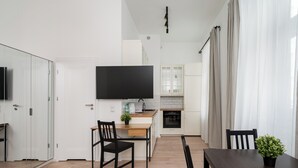 A modern kitchen with white cabinets, a wooden countertop, and a flat-screen TV mounted above the island.