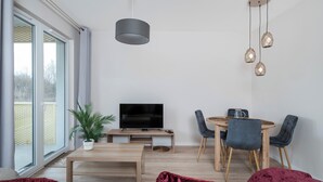 Ein modernes Wohnzimmer mit Fernseher, Esstisch und Stühlen.
