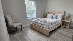 A bedroom with a wooden bed, a chair, a nightstand, and a window. - Beautiful New Home in Citrus Springs, sleep 6 (Citrus Springs)