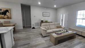 A spacious living room with a beige sofa, a coffee table, and a painting on the wall. - Beautiful New Home in Citrus Springs, sleep 6 (Citrus Springs)