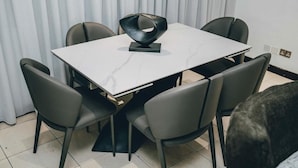 A modern dining area with a marble table, six chairs, and a unique black sculpture centerpiece. - Luxury 3BR Alema Court-Airport Close (Accra)