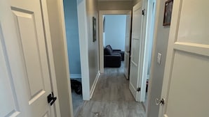 A hallway with white doors, a wooden floor, and a ceiling light.