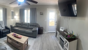 A living room with a sofa, a recliner, a coffee table, and a TV mounted on the wall.