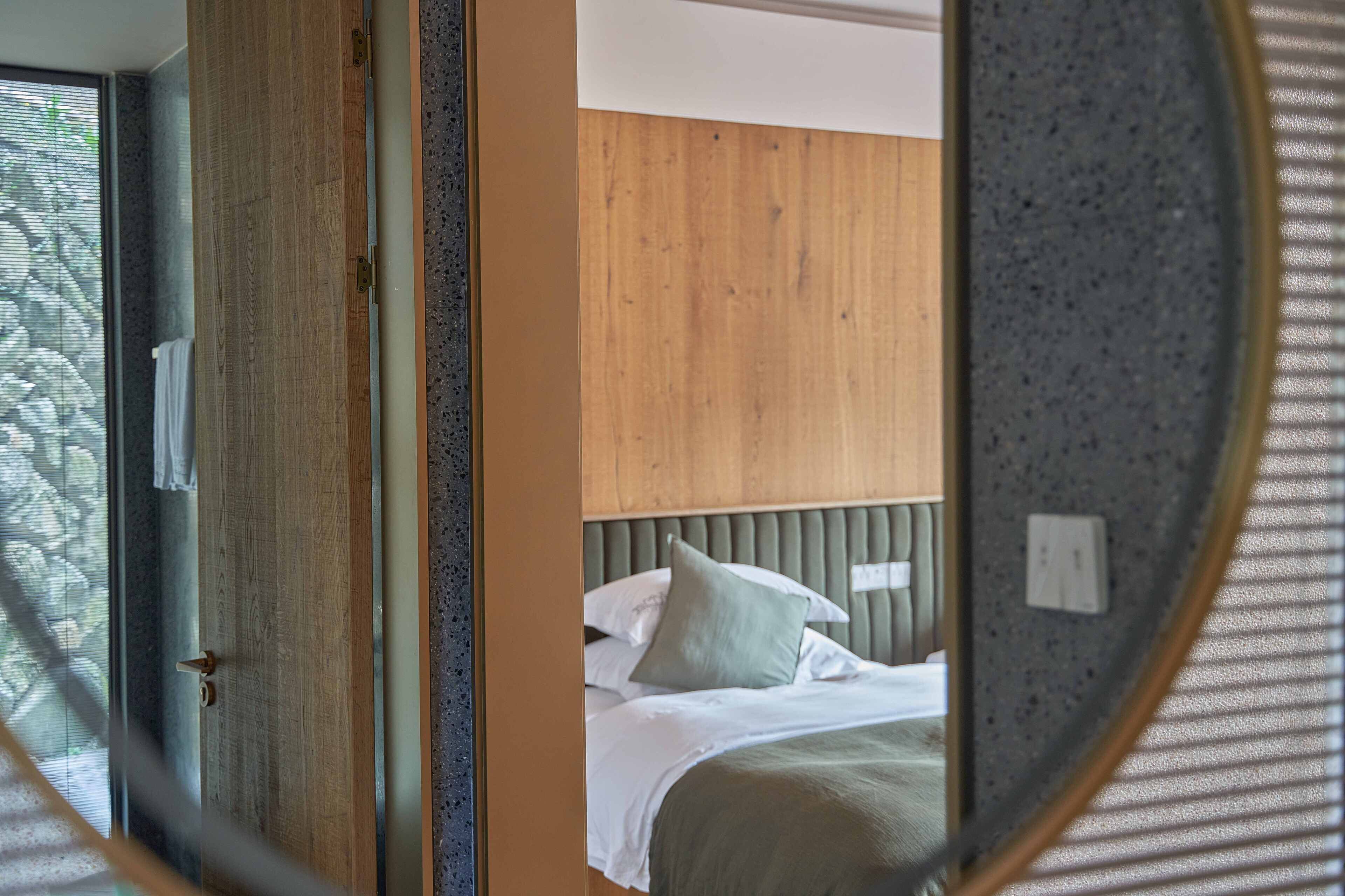 Un dormitorio con cabecera de madera, una cama con ropa blanca y una ventana con persianas.