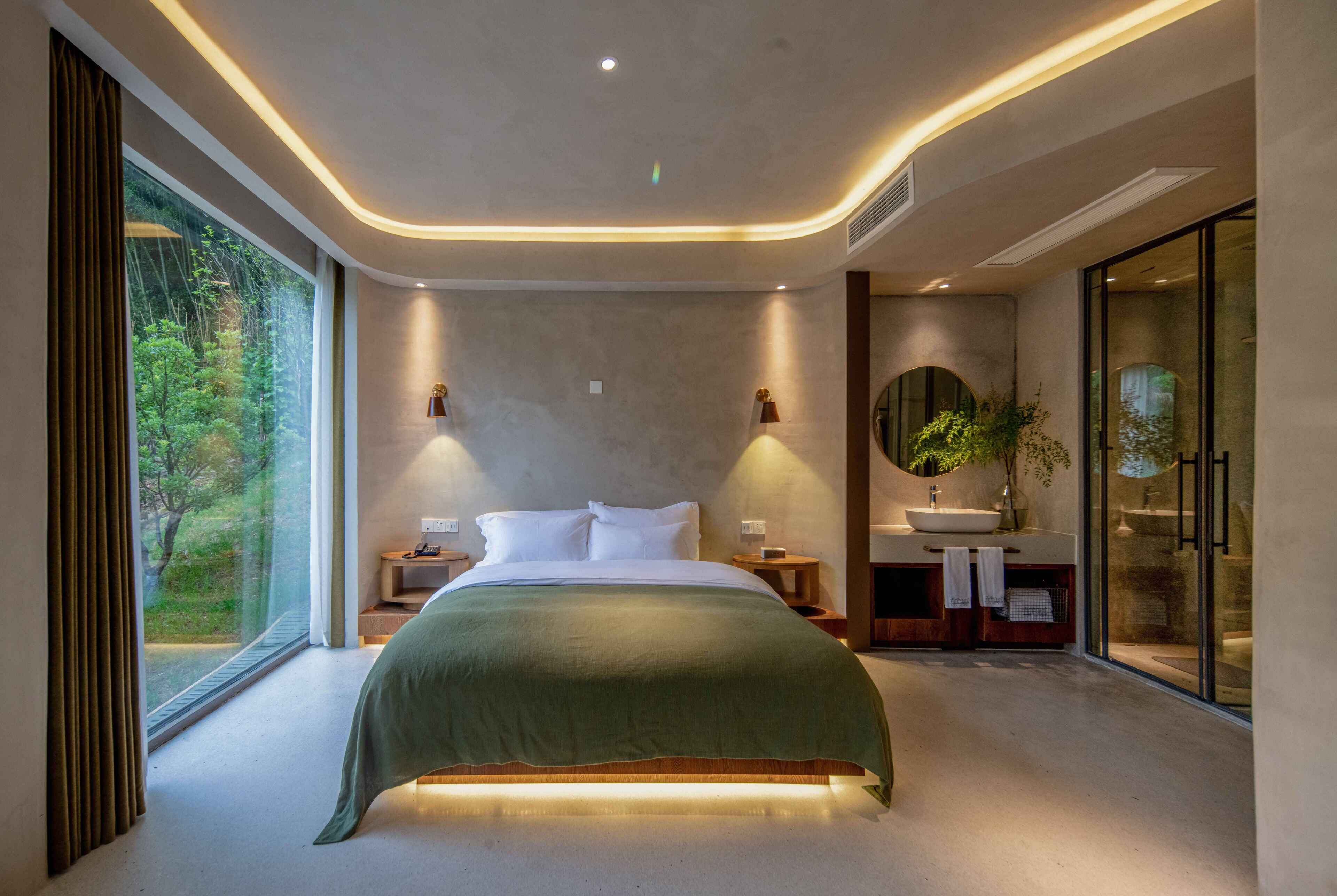 Un dormitorio moderno con una cama grande, mesitas de noche, un lavamanos integrado y una ducha de vidrio.