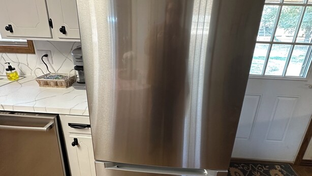 A stainless steel refrigerator in a kitchen with white cabinets and a window. - Lake Life is Calling! Minutes to Cypress Bend Park, private 5-Acre Retreat (Florien)