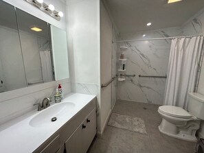 Een moderne badkamer met een wit wastafelmeubel, spiegel en douchegedeelte.