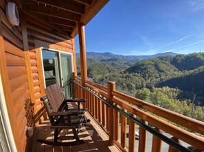 A wooden cabin with a balcony, a bench, and a door leading to an interior space. - Gatlinburg New Year’s Week Resort Villa with Mountain Views (Gatlinburg)