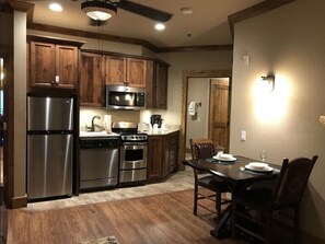 A kitchen with wooden cabinets, stainless steel appliances, a dining table with chairs, and a ceiling fan. - Gatlinburg New Year’s Week Resort Villa with Mountain Views (Gatlinburg)