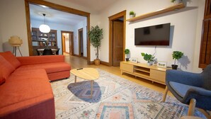 Ein Wohnzimmer mit Sofa, Couchtisch, Fernseher und Bücherregal.