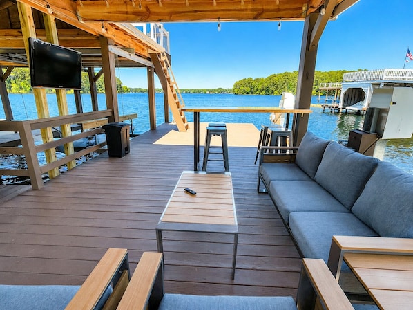 A wooden deck with a sofa, a table, and a TV.