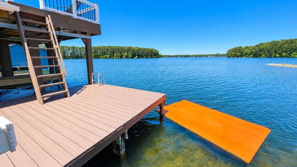 A wooden dock extending into a lake with a clear view of the surrounding forest. - NEW! Main lake Family-Friendly retreat with private dock, game room, & fire pit! (Littleton)