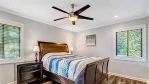 A bedroom with a bed, nightstands, a ceiling fan, and windows. - NEW! Main lake Family-Friendly retreat with private dock, game room, & fire pit! (Littleton)