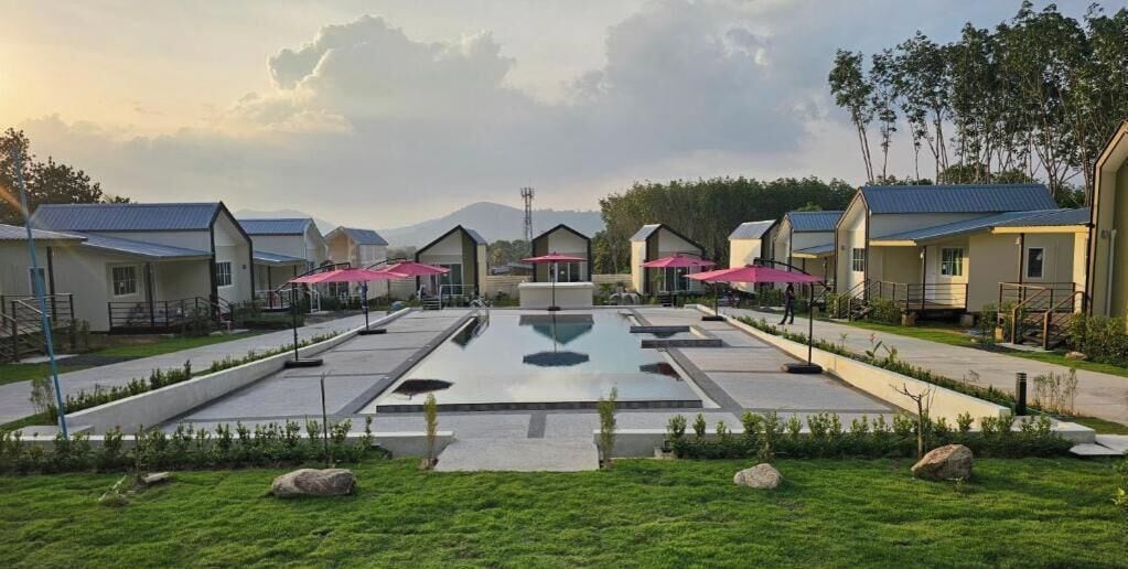 A hotel with multiple rooms, a central pool, and a mountainous backdrop.