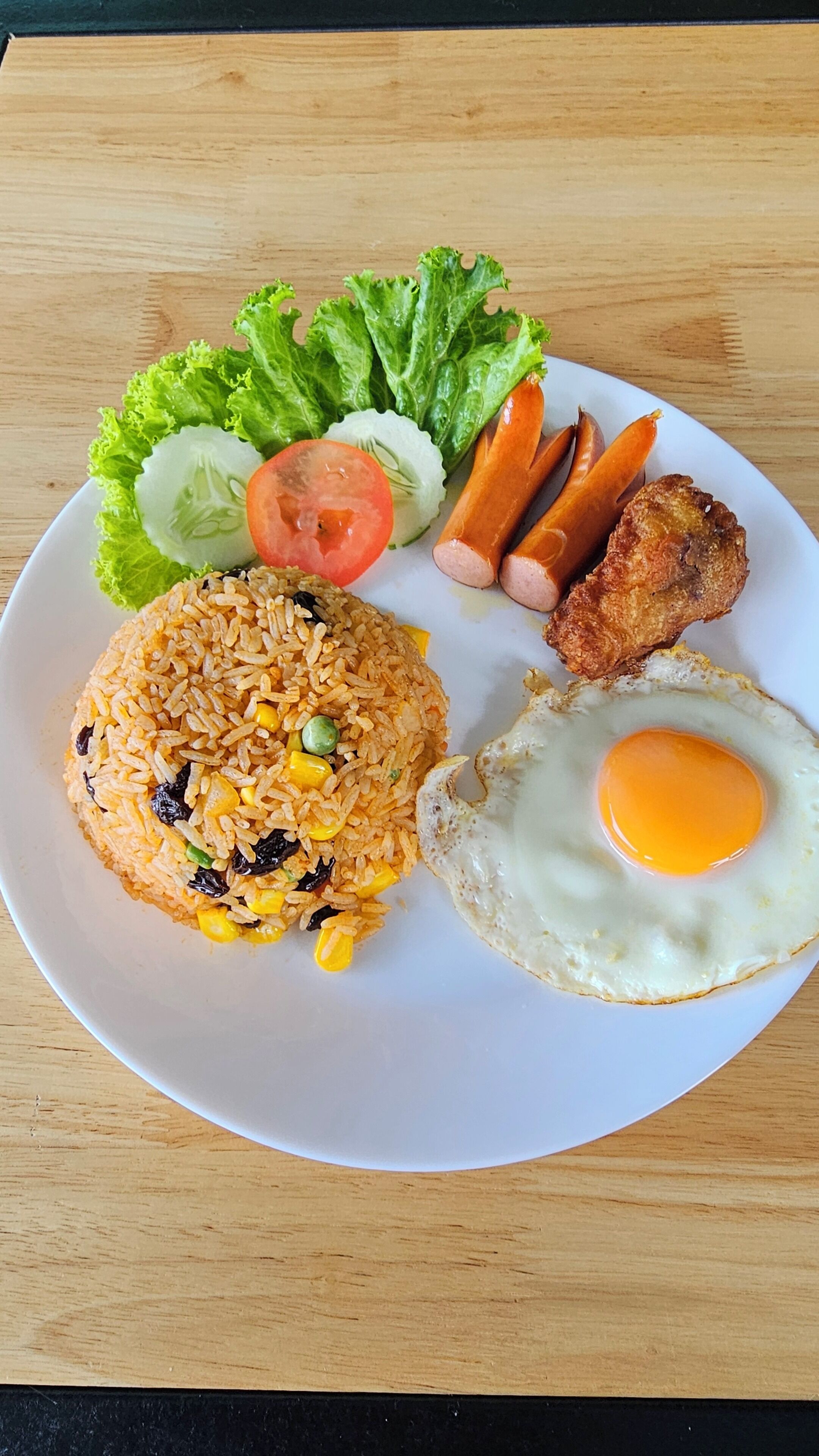 A plate of fried rice, a fried egg, and a side of vegetables and meat.