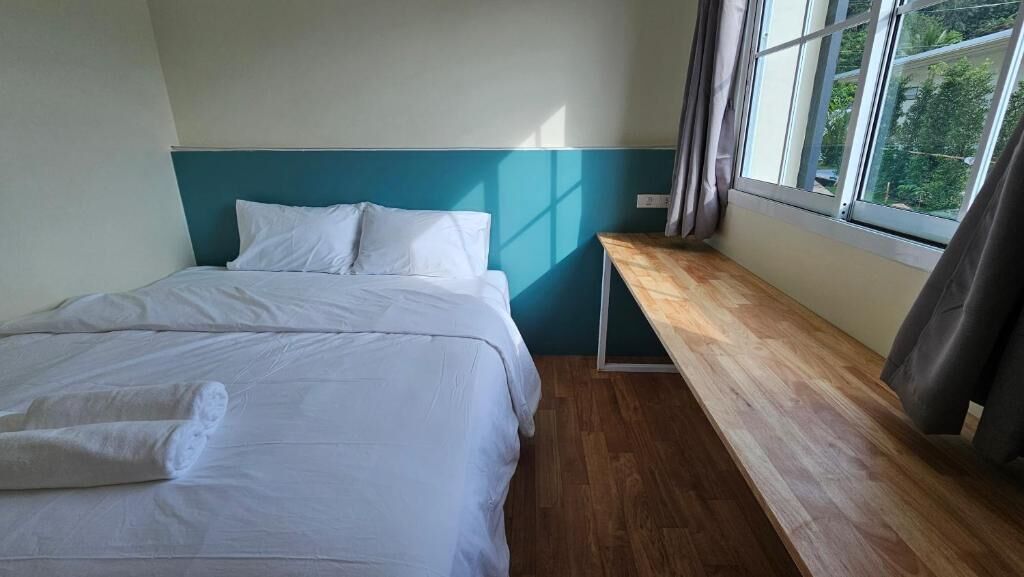 A bedroom with a bed, a wooden bench, and a window.