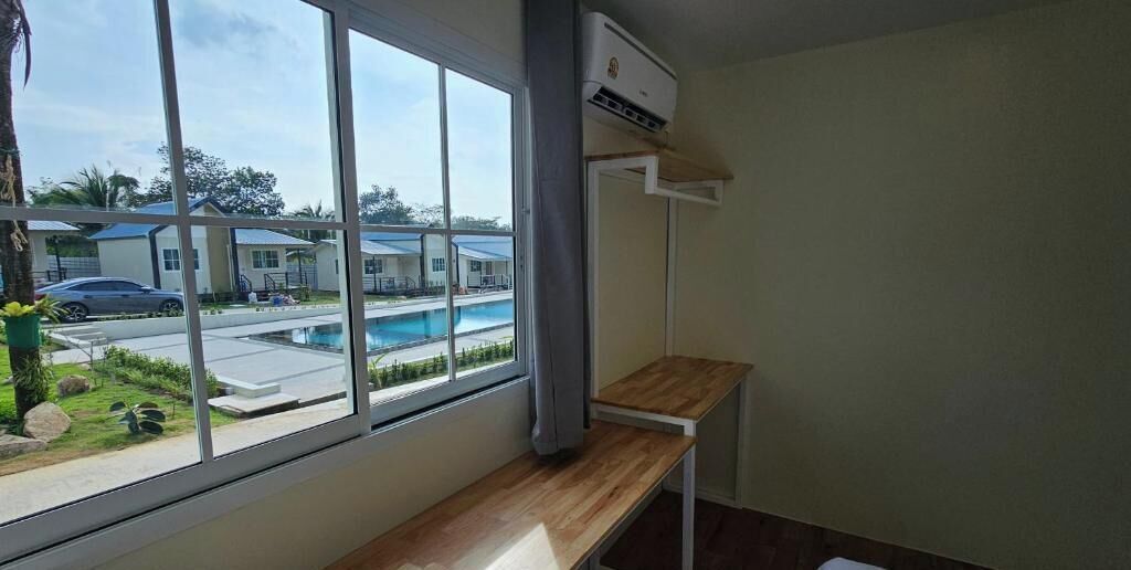 A room with a large window, a wooden bench, and an air conditioning unit.