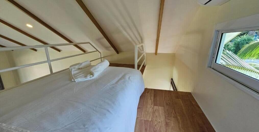 Quarto com uma cama, janela e chão de madeira.