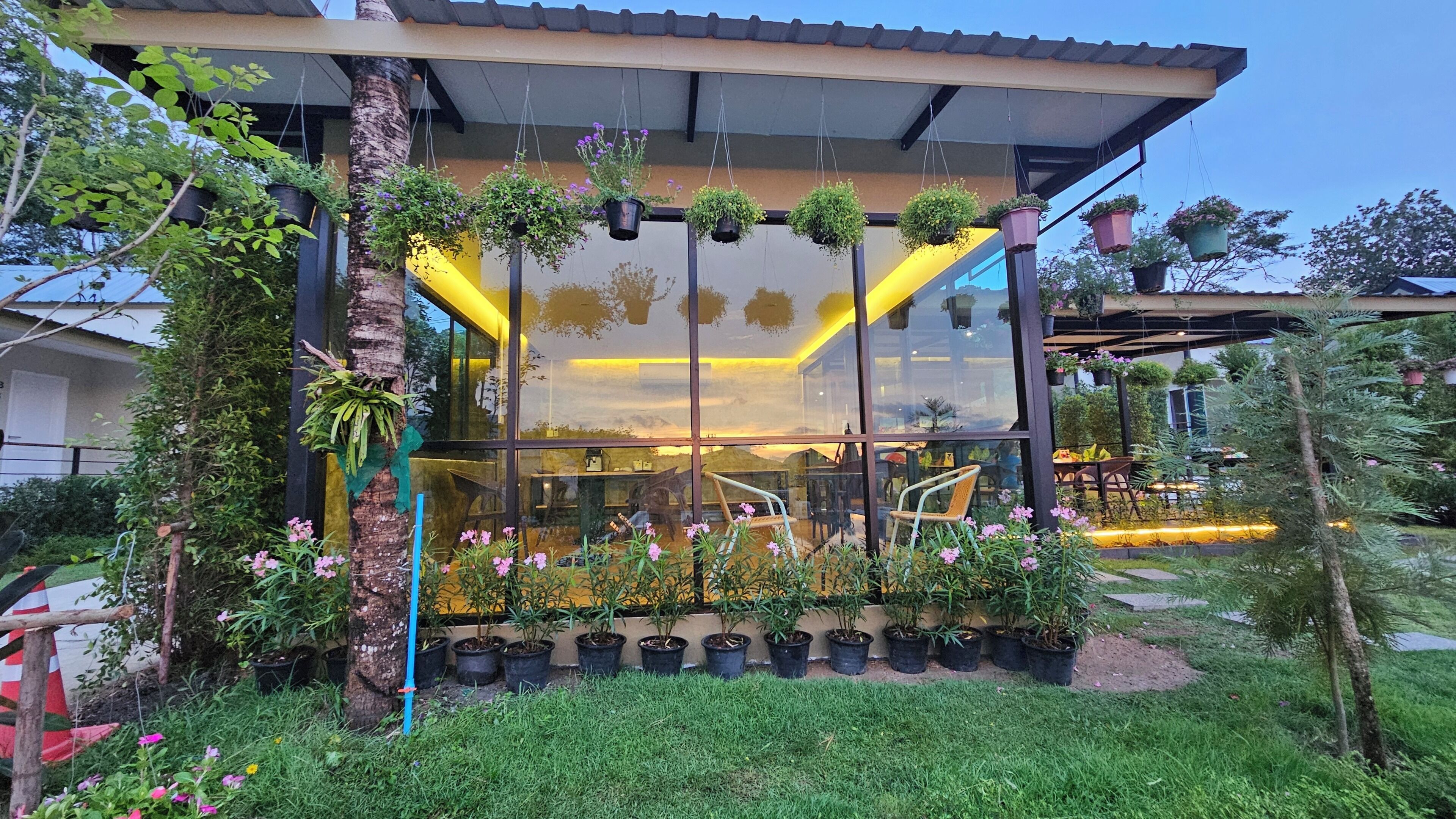 Un edificio moderno con amplias ventanas, plantas en macetas y asientos al aire libre.