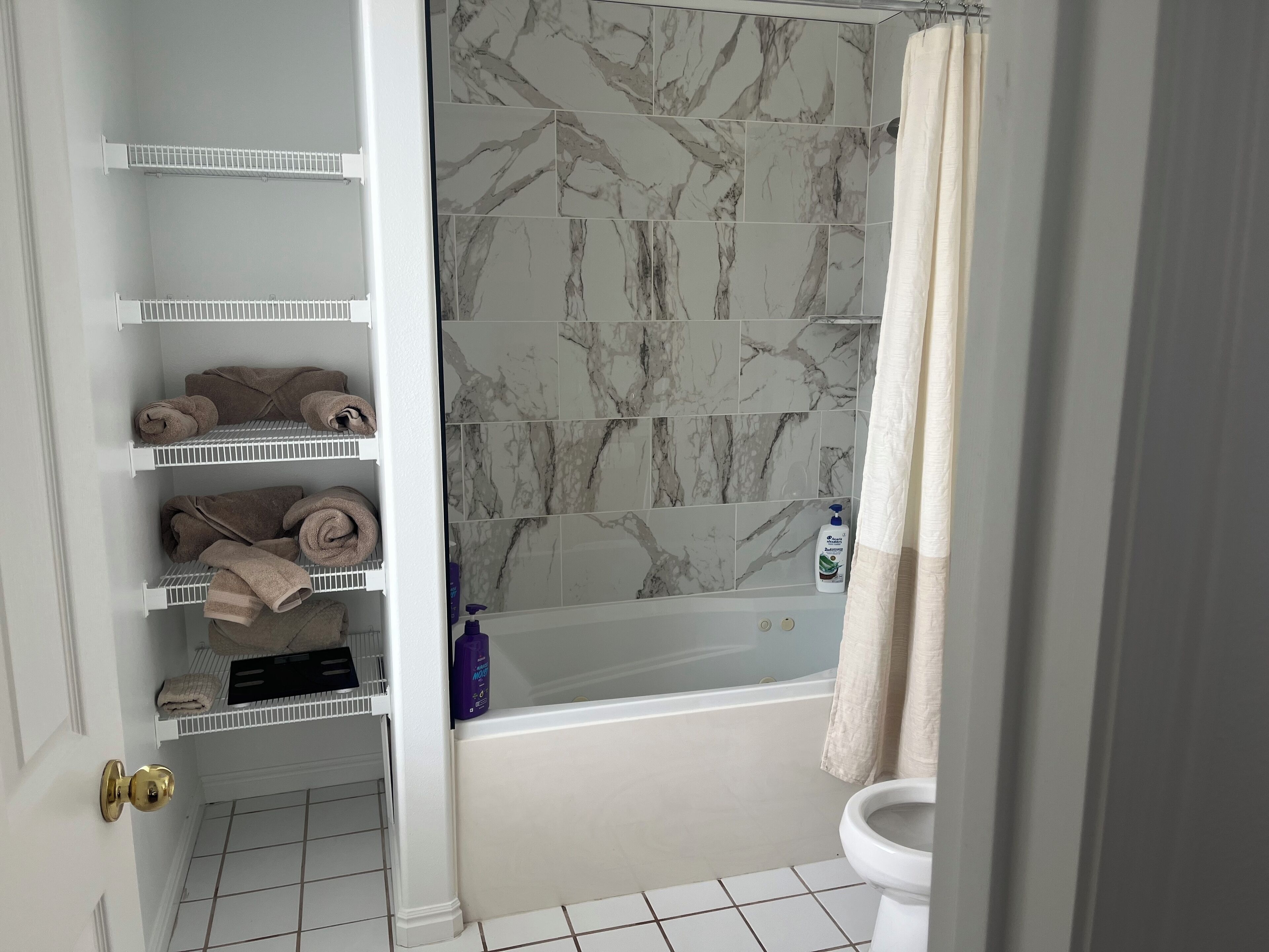 Een badkamer met een bad, toilet en een plank met handdoeken.