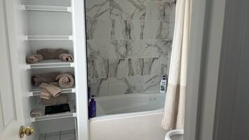 Een badkamer met een bad, toilet en een plank met handdoeken.