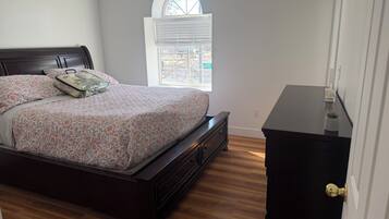 A bedroom with a bed, a dresser, a window, and a door.