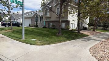 A residential street with a house featuring a front yard, a driveway, and a parked car.