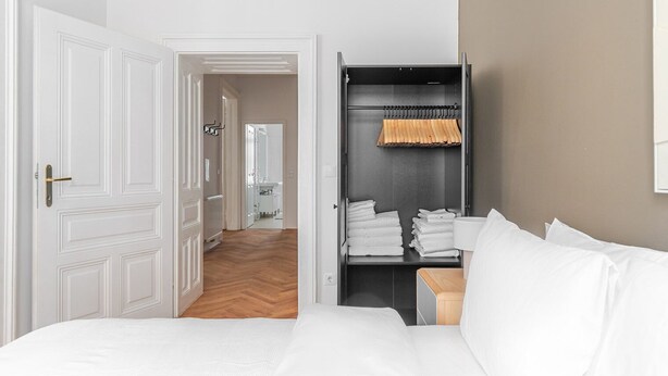 A hotel room with a bed, a wardrobe, and a bathroom visible through an open door. - Blueground | Neubau, view, nr Museumsquartier (Vienna)