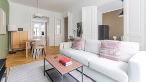 A modern living room with a white sofa, a wooden coffee table, and a dining area with a chair and table. - Blueground | Neubau, view, nr Museumsquartier (Vienna)