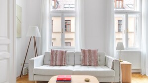 Ein modernes Wohnzimmer mit einem grauen Sofa, zwei Kissen, einem Holztisch und einer Stehlampe.